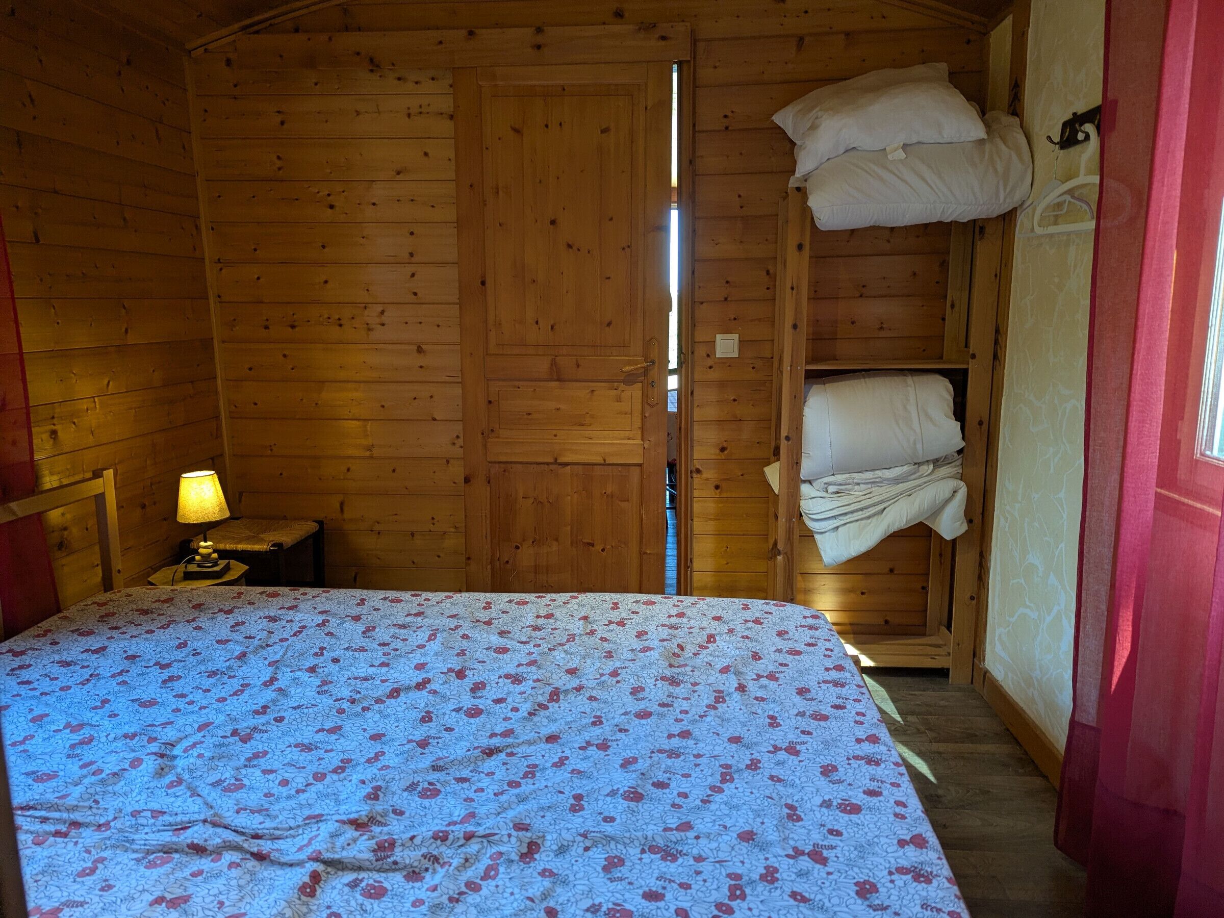 Une chambre dans un chalet en bois, avec un lit, une table de chevet et une fenêtre.