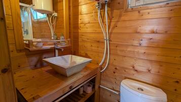Een houten badkamer met een stenen wastafel, toilet en raam.
