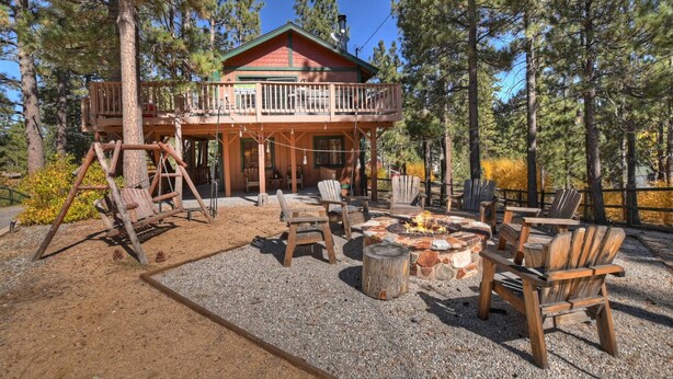 A cabin with a deck, outdoor seating, and a fire pit.