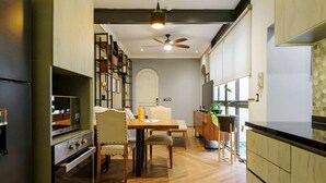 A modern kitchen with wooden cabinets, a dining area with a table and chairs, and a ceiling fan. - w* | Stylish 2BR in Cuauhtemoc (Ciudad de México)