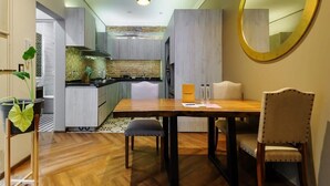 A modern kitchen with a central island, a dining area with a wooden table and chairs, and a large mirror on the wall. - w* | Stylish 2BR in Cuauhtemoc (Ciudad de México)