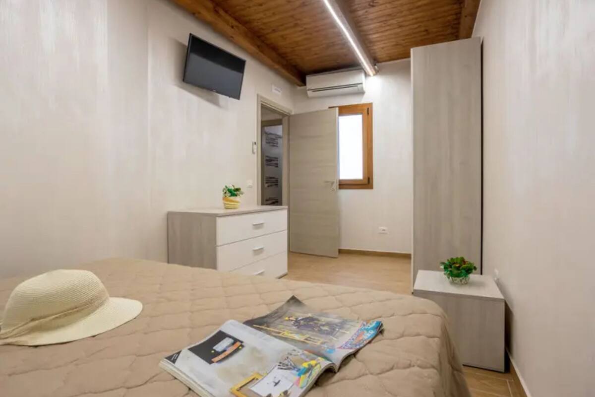 A bedroom with a bed, a television, a wardrobe, and a window.