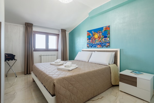 A hotel room with a bed, a nightstand, a painting on the wall, and a window with curtains. - Azzurra Apartments (Balestrate)