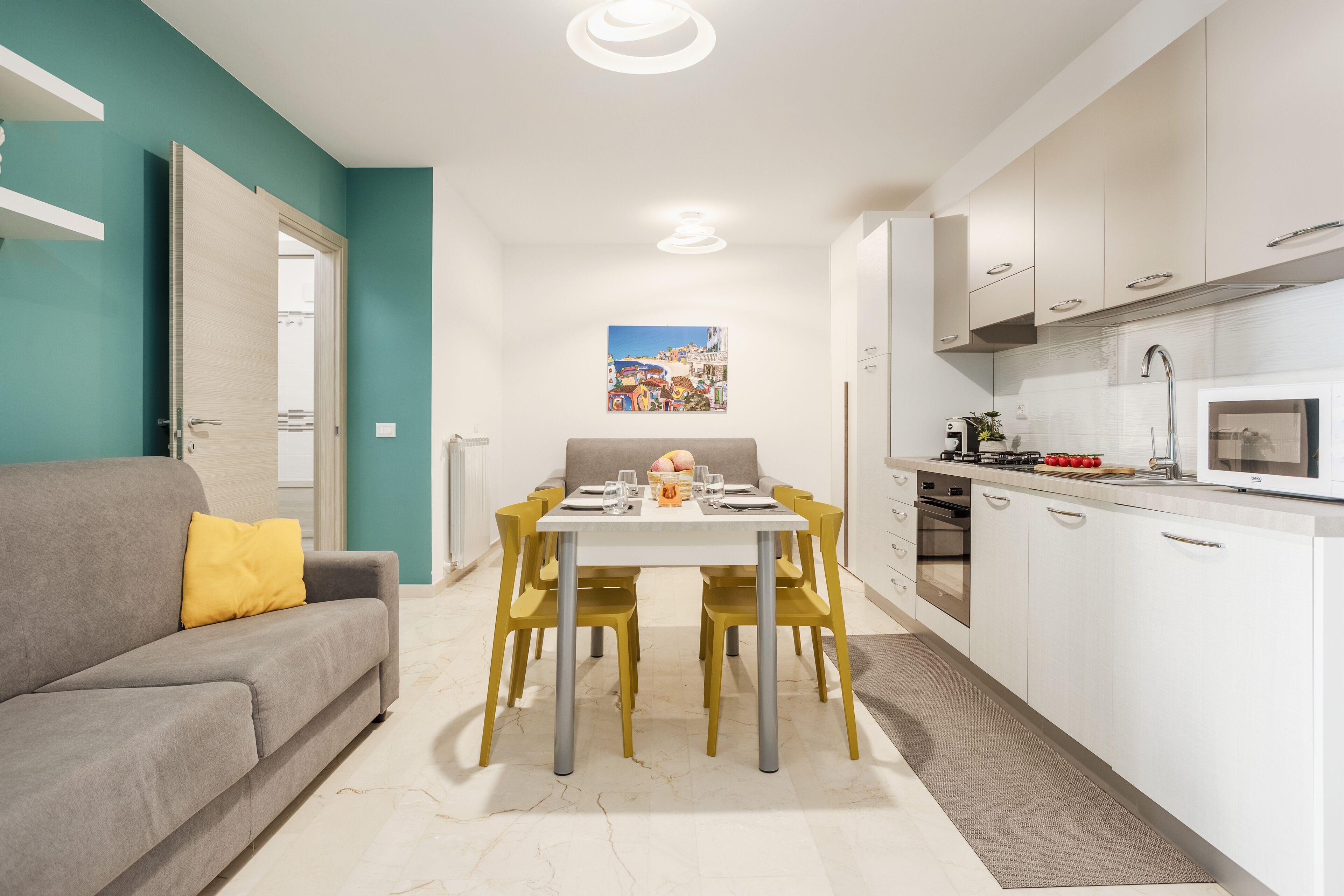 A modern kitchen with white cabinets, a microwave, and a dining area with a table and chairs.