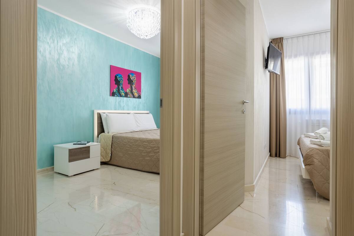 A modern bedroom with a bed, nightstand, and a painting on the wall.
