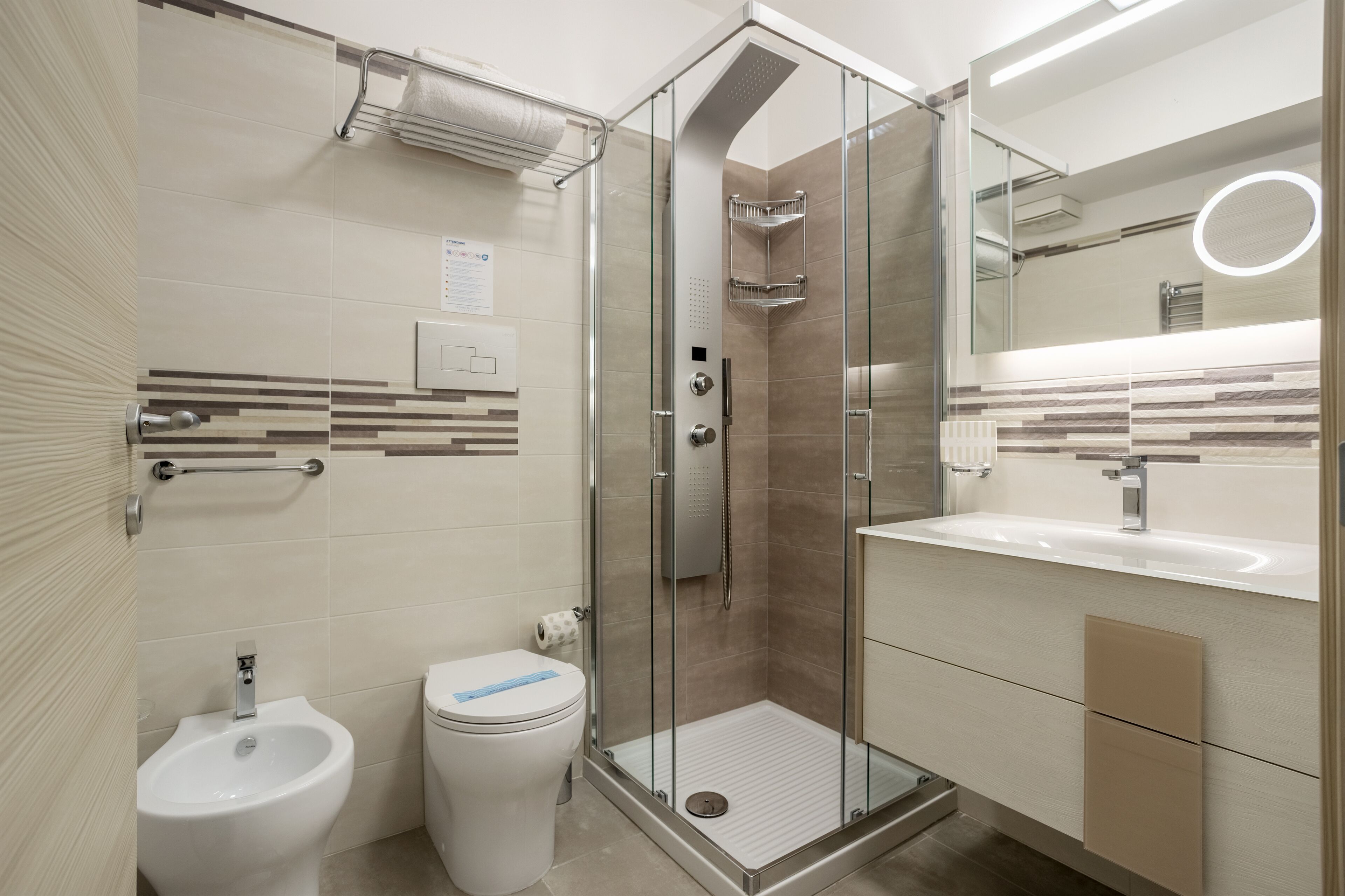 A modern bathroom with a glass-enclosed shower, a bidet, a toilet, and a vanity with a mirror.
