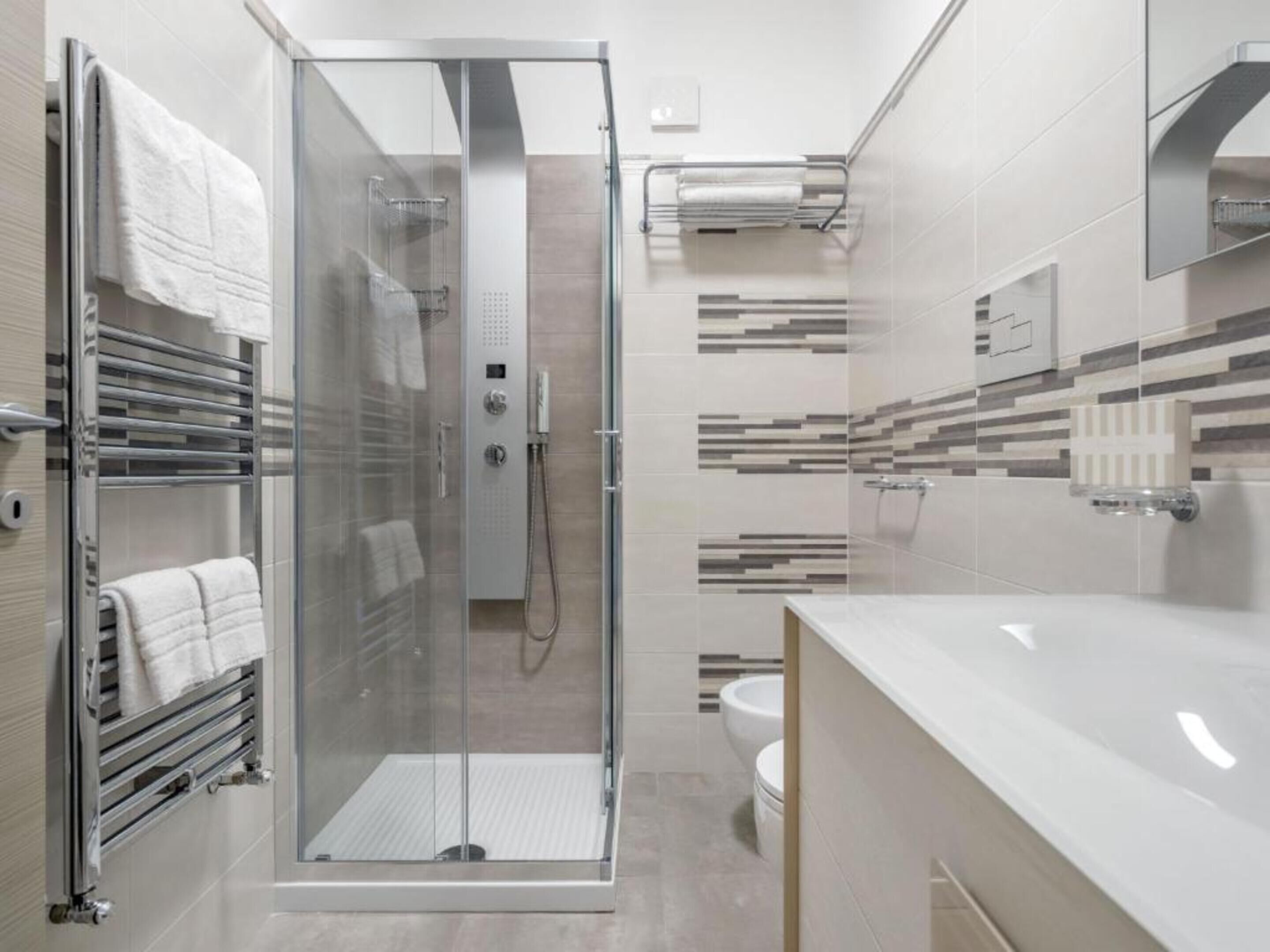 A modern bathroom with a glass-enclosed shower, a toilet, and a vanity with a mirror.