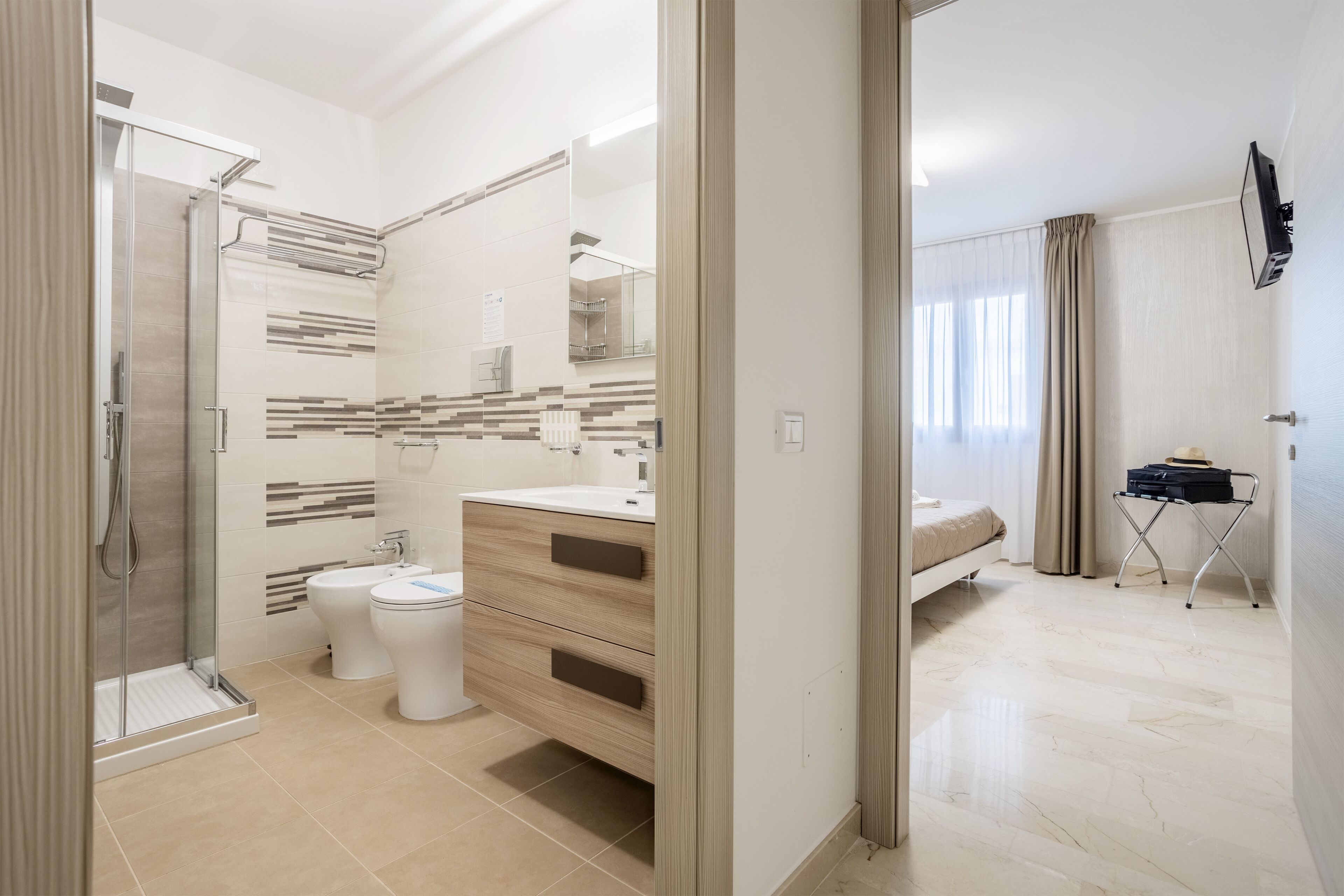 A modern bathroom with a glass shower, two toilets, a sink, and a vanity.