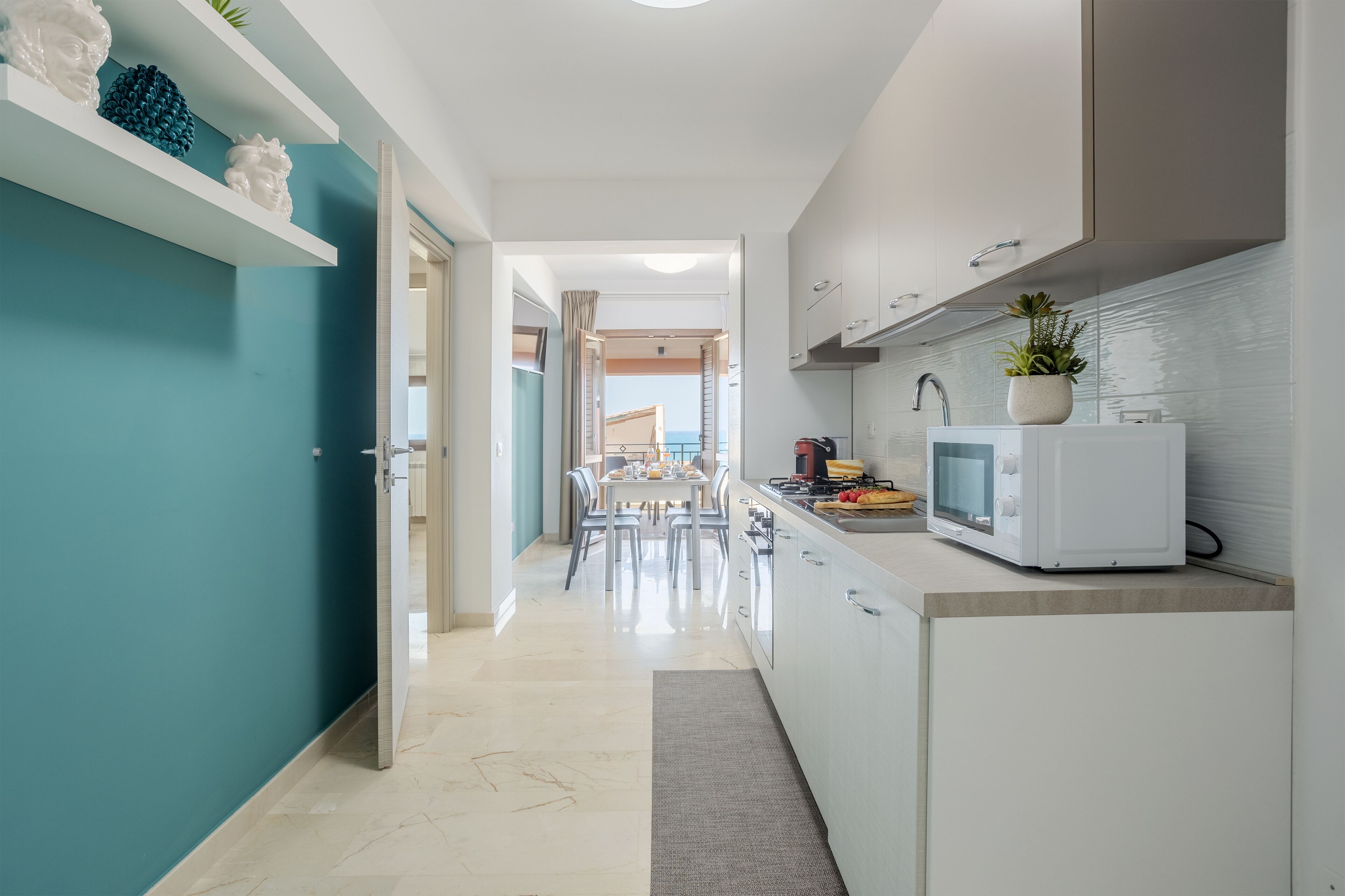 A narrow kitchen with white cabinets, a microwave, and a small countertop.
