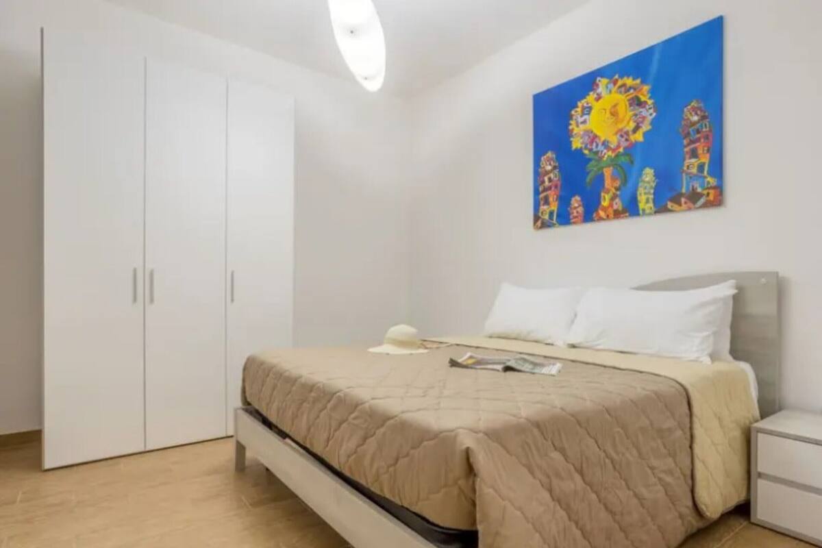 A bedroom with a bed, a nightstand, a wardrobe, and a painting on the wall.
