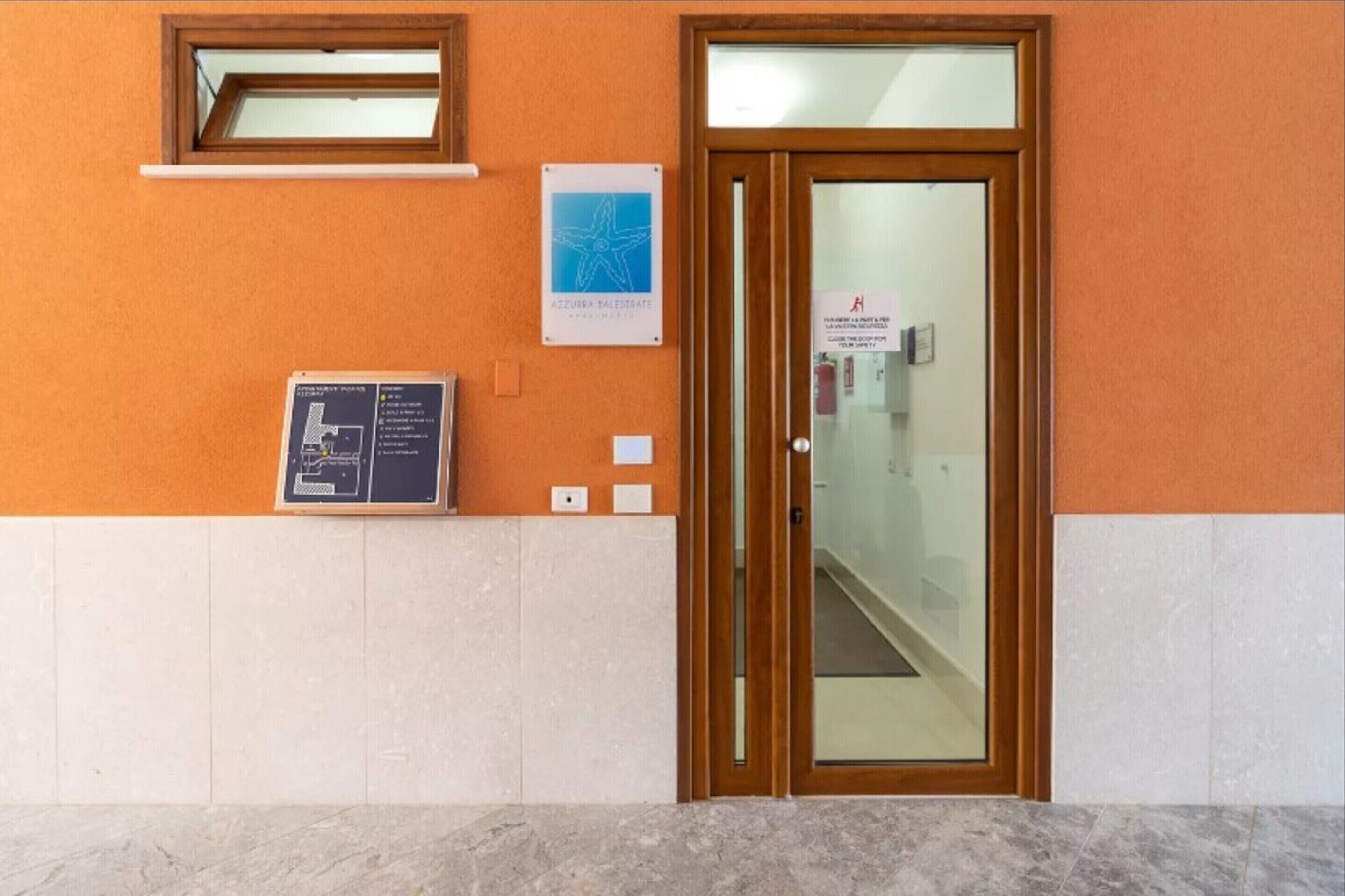 A reception area with a wooden door, a small window, and a signboard.