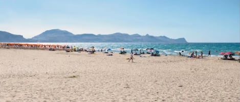 A beach with people, umbrellas, and a clear sky.