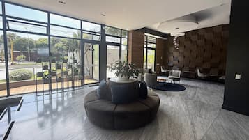 A modern lobby with a curved sofa, seating area, and large windows offering views of the outdoors.