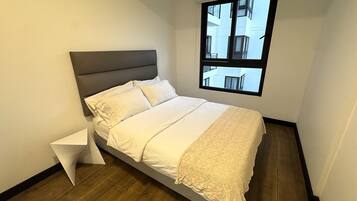 A bedroom with a bed, a window, and a wooden floor.