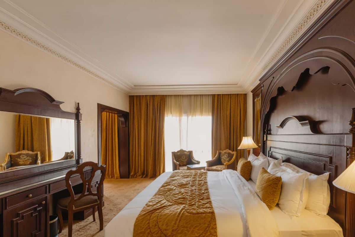 A hotel room with a large bed, a desk, and a chair.