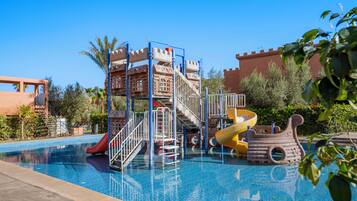 A swimming pool with a castle-themed play area, including slides and a ship-shaped structure.
