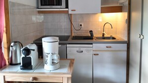Una cocina compacta con microondas, cafetera y lavavajillas Bosch.
