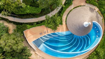 Relax by the serene, circular pool surrounded by lush greenery and a winding pathway.