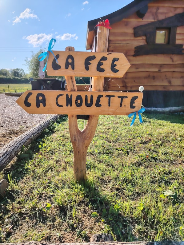 Ein hölzernes Wegweiser mit Pfeilen, die zu 'CA FEE' und 'CA CHOUETTE' zeigen.