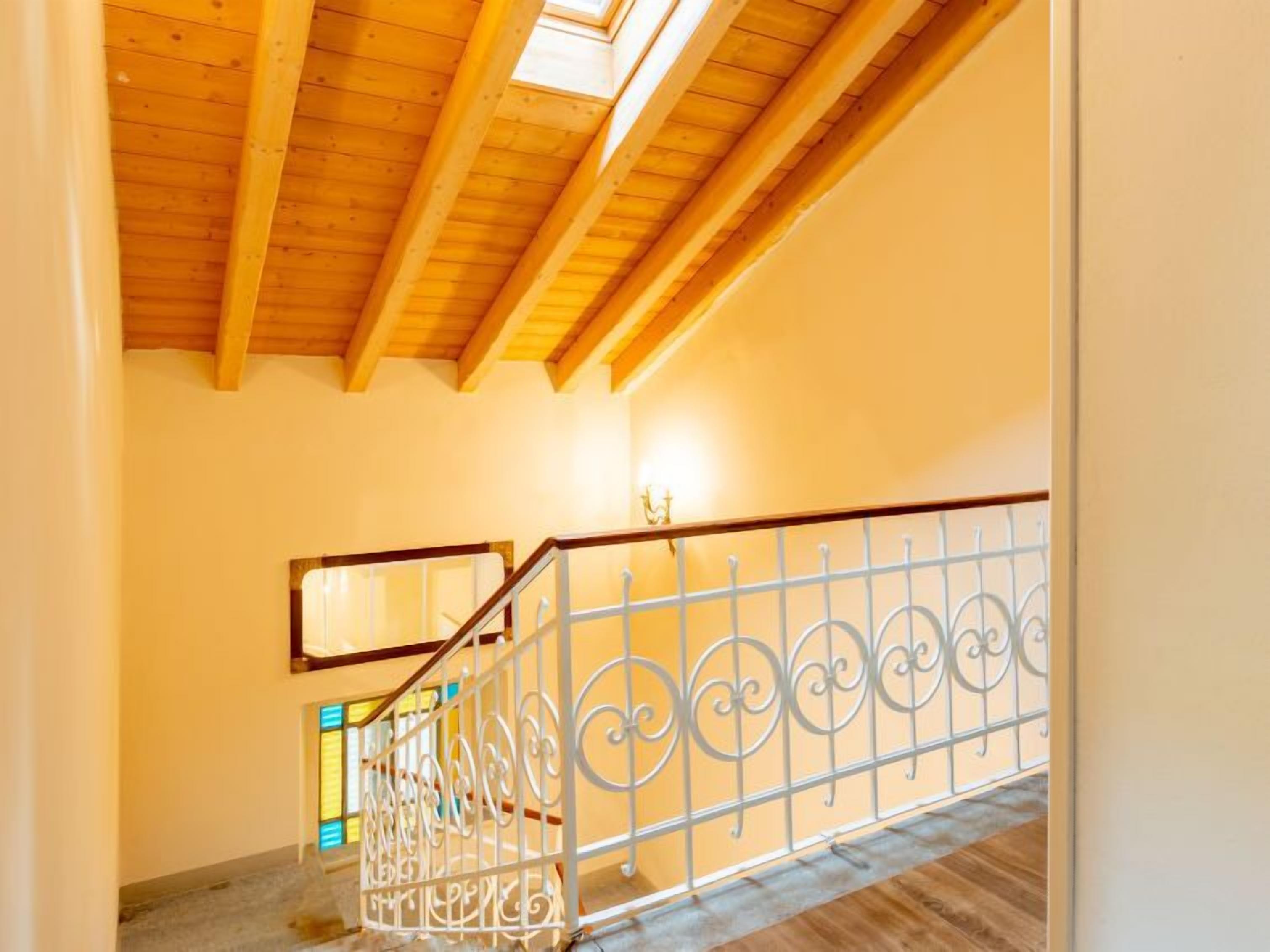 A wooden staircase with a metal railing and a skylight above.