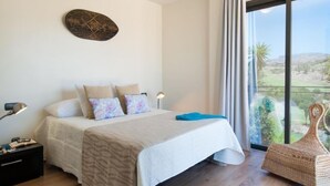 Un dormitorio con cama, mesita de noche, lámpara, ventana con vistas y decoración en la pared.