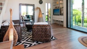 Una sala de estar moderna con un ventanal grande, un conjunto de sofá, un televisor y un espejo decorativo.