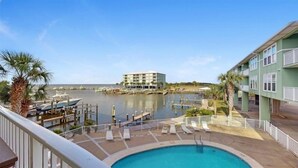 Un hôtel avec piscine, un port de plaisance avec des bateaux et une vue sur l’eau.