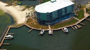 Vue aérienne d’un hôtel doté d’un toit incurvé, de bateaux amarrés et d’une plage à proximité.