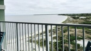 Un balcon donnant sur une plage et un pont situé au loin.