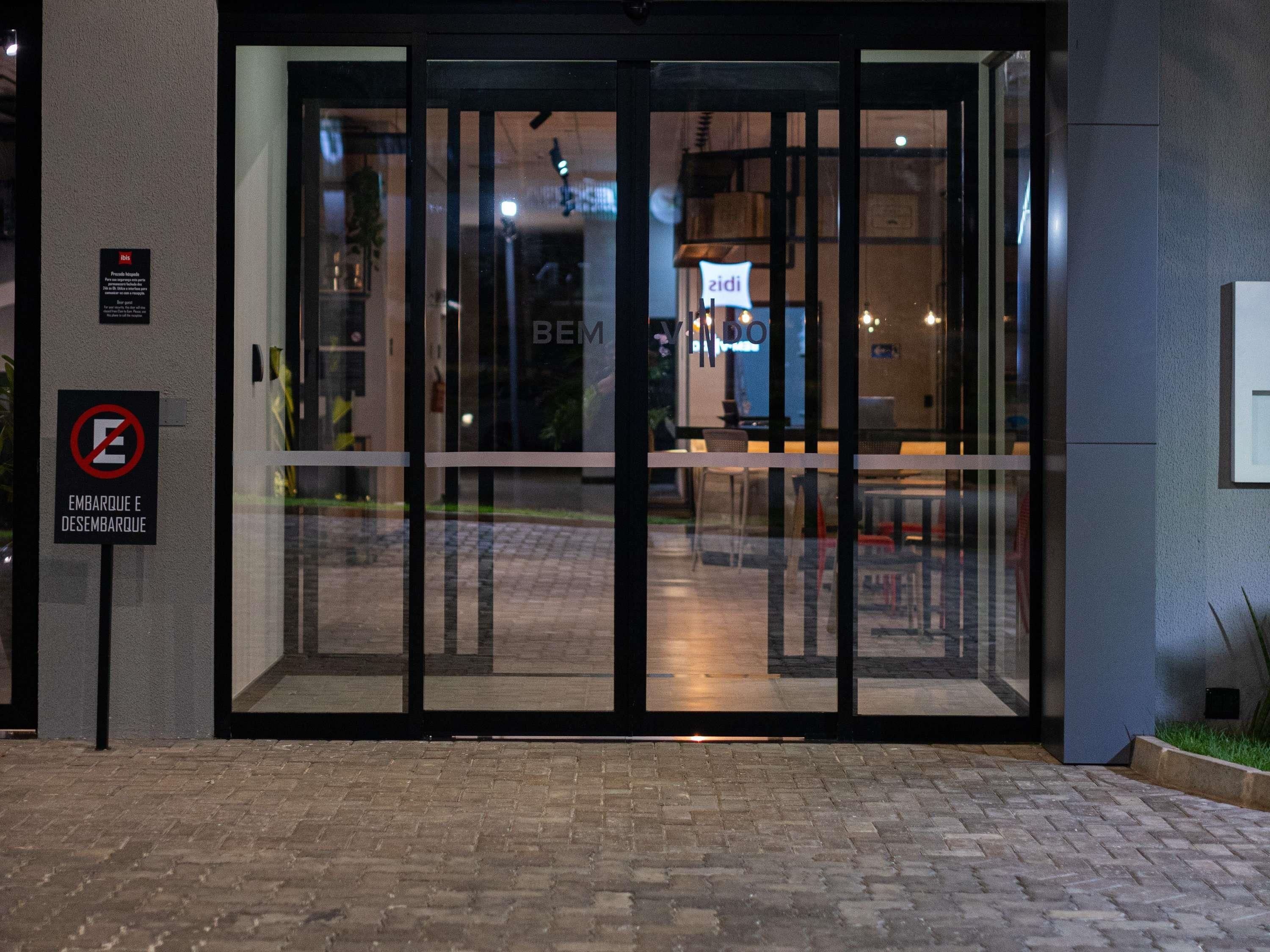 A hotel entrance with a glass door, a no smoking sign, and a sign indicating the hotel name.