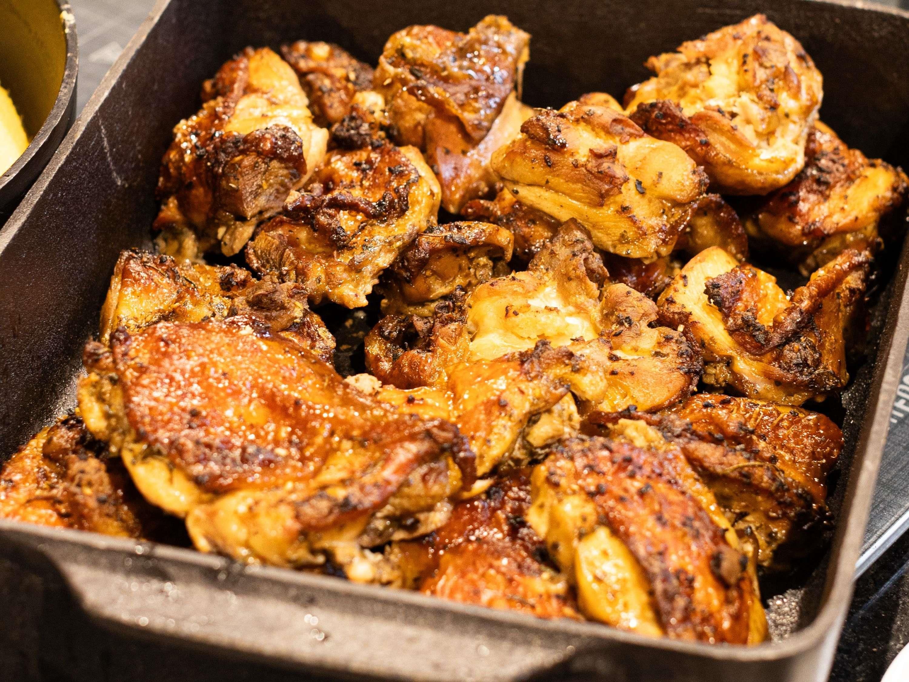 Uma travessa de frango cozido com temperos à vista.