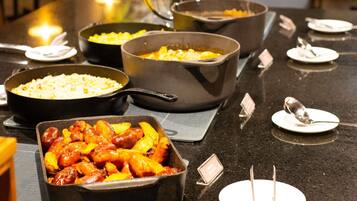 Una mesa de buffet con diversos platos, entre ellos un pastel de carne, una bandeja de arroz y un plato con carne y verduras.