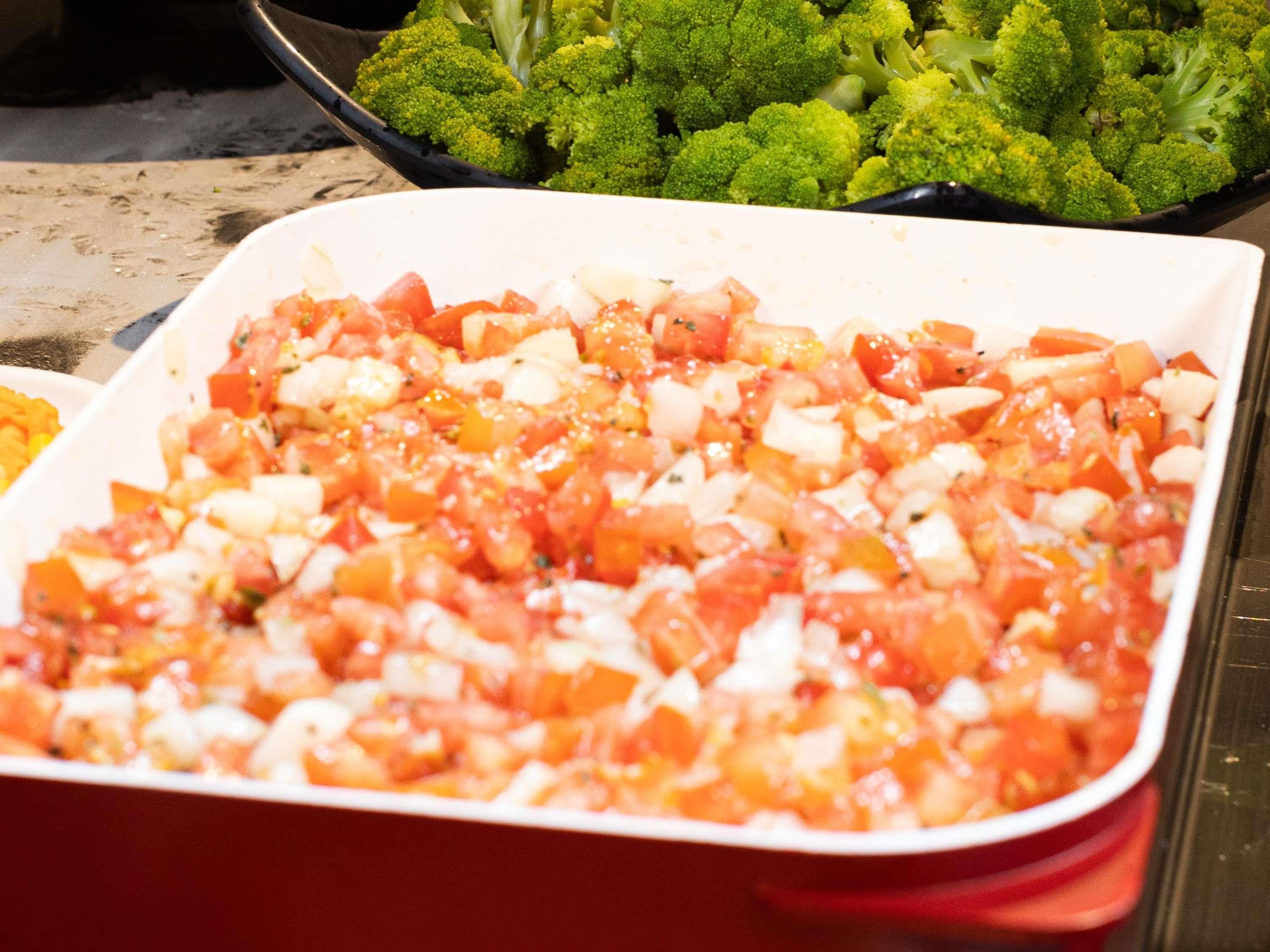 Un plato de tomates en cubos y queso en un recipiente blanco.