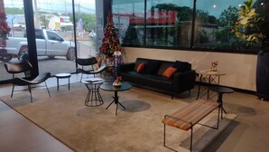 A modern interior with a sofa, chairs, tables, and a Christmas tree. - Ibis Barra Do Garcas (Barra do Garcas)