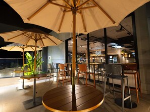 A restaurant with outdoor seating, including round tables and chairs, under large umbrellas. - Ibis Barra Do Garcas (Barra do Garcas)