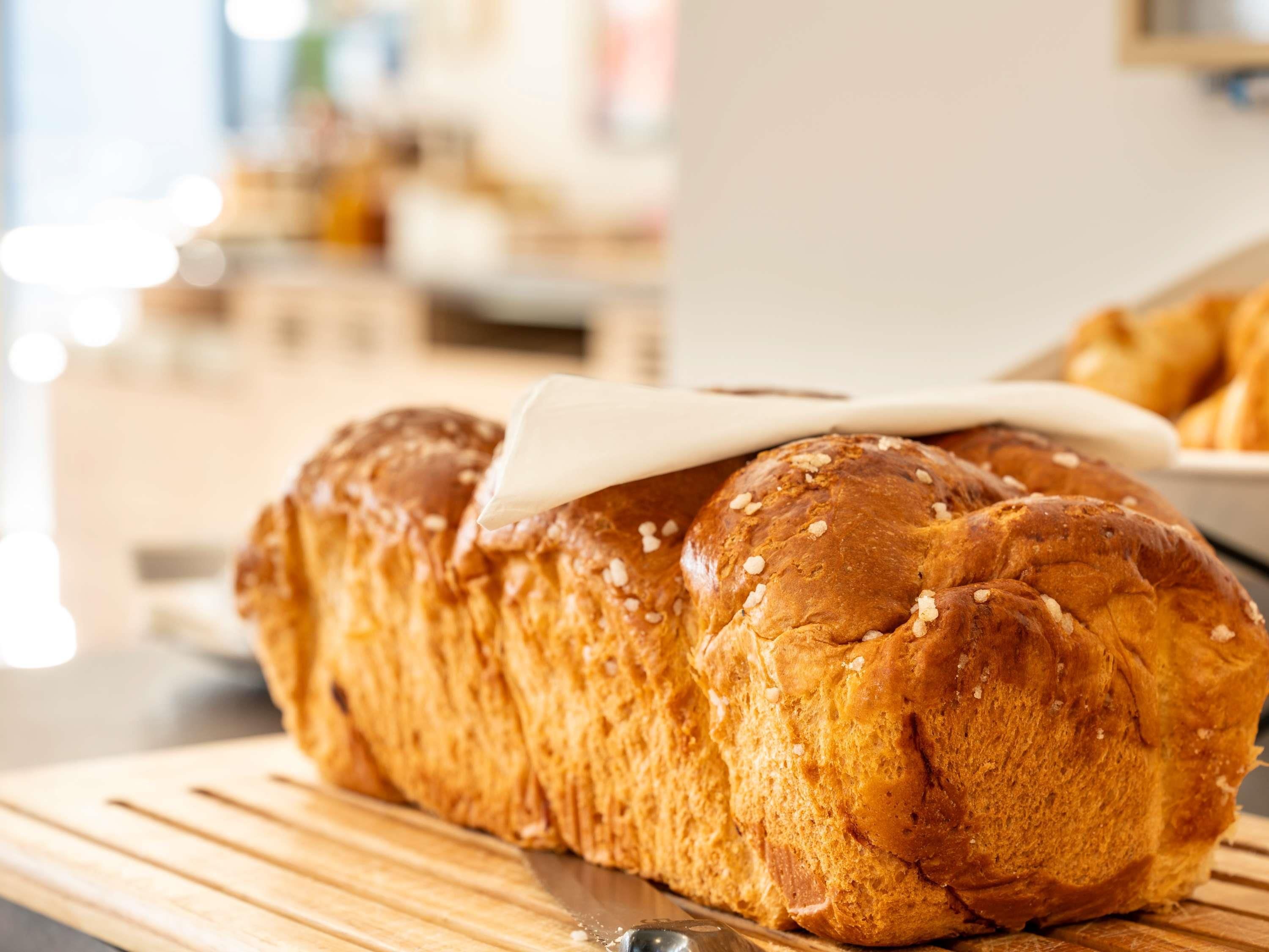 A loaf of bread with sesame seeds on a wooden cutting board.