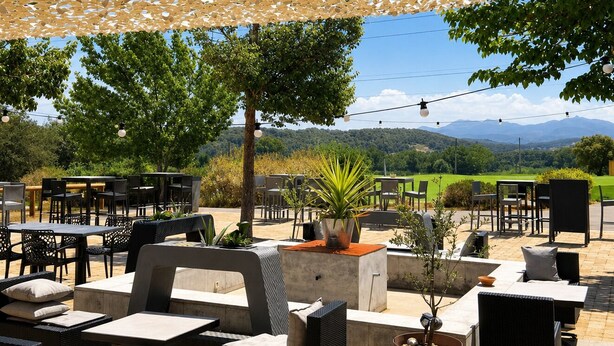 An outdoor seating area with tables and chairs, a pergola overhead, and a view of a green landscape with hills. - Ibis Styles Cabriès Aix-En-Provence Tgv  (Cabries)