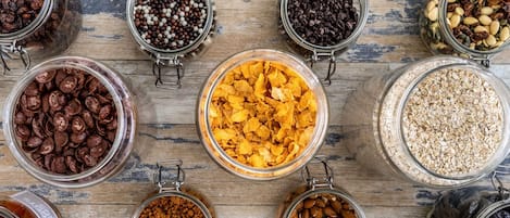 Une variété d’aliments présentés dans des bocaux en verre, posés sur une surface en bois.