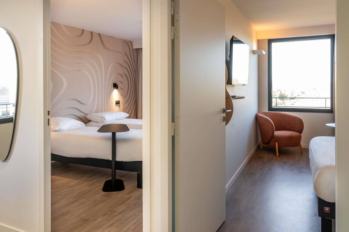 Une chambre d’hôtel moderne, équipée d’un lit, d’une table de chevet et d’une chaise.