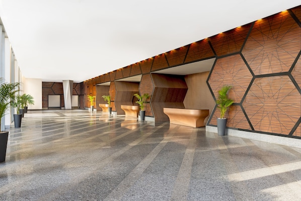 Un hall espacioso con suelo pulido, una recepción moderna y plantas en macetas.