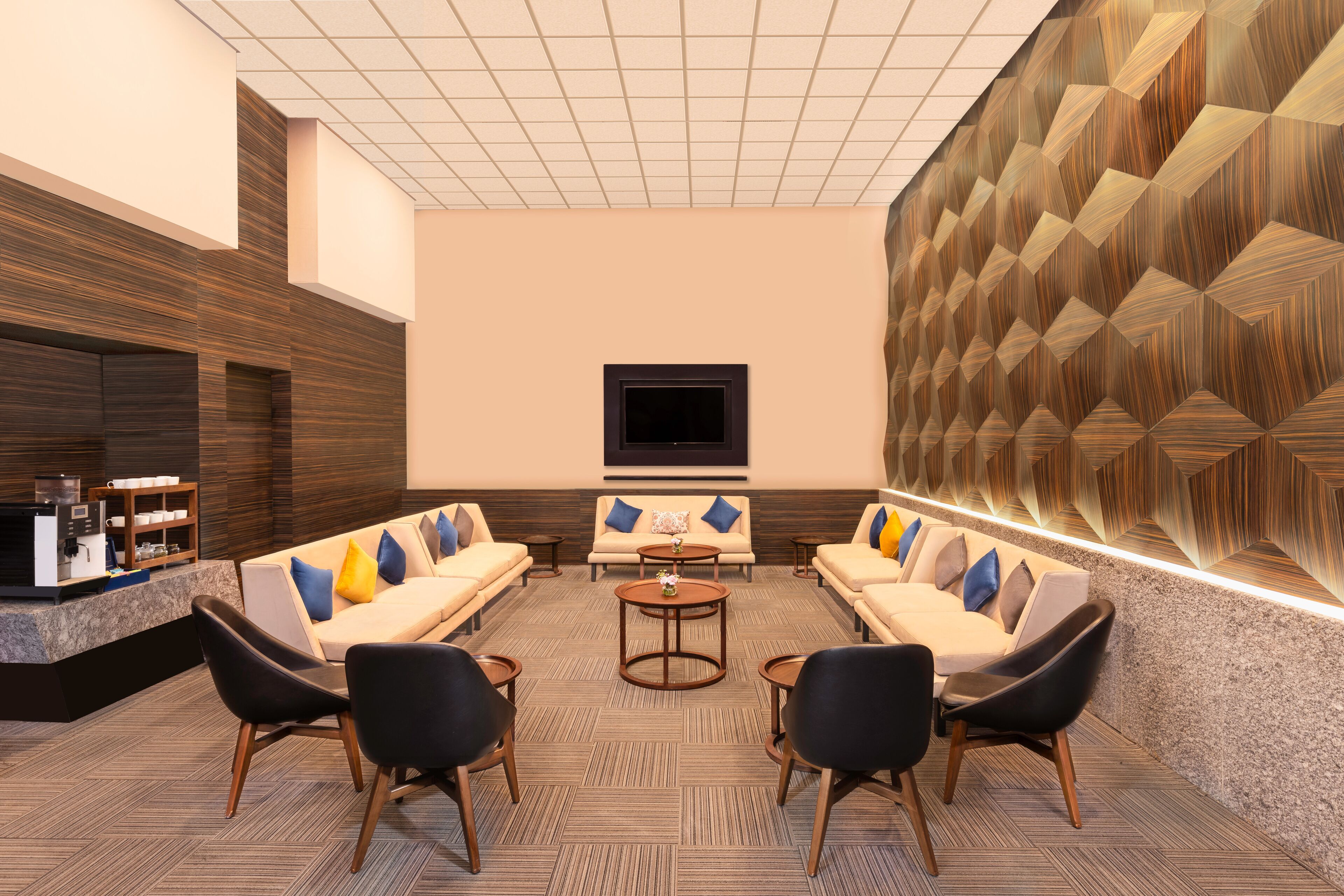 A modern lobby with a sofa set, a coffee station, and a patterned wall.
