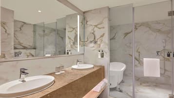 A modern bathroom with two sinks, a large mirror, and a glass shower enclosure.