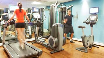 Ein Fitnessstudio mit Laufbändern, Crosstrainern und Gewichten.