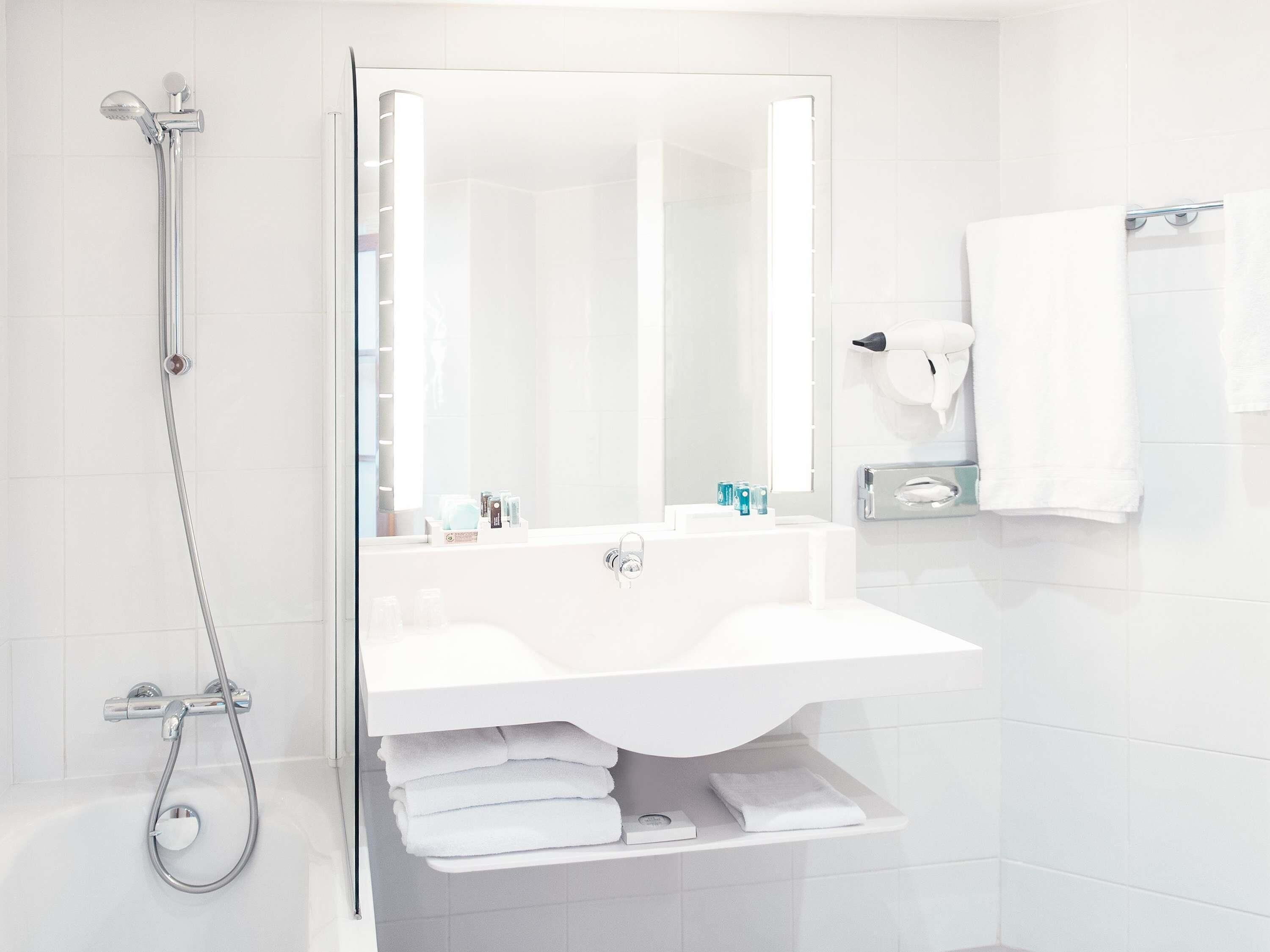 Ein modernes Badezimmer mit einer gläsernen Dusche, einem weißen Waschbecken und einem Spiegel.