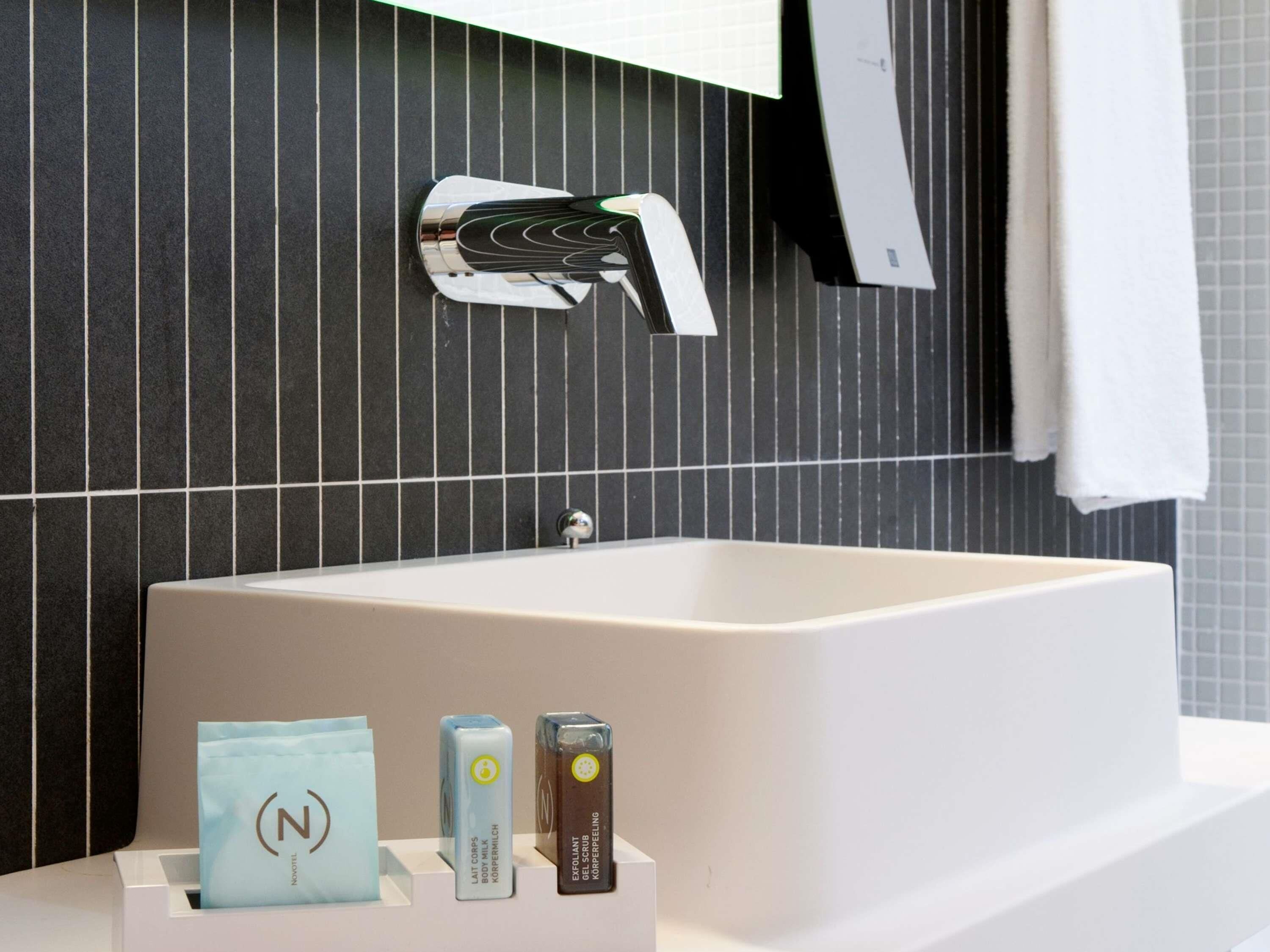 A bathroom with a modern sink, a towel rack, and toiletries.