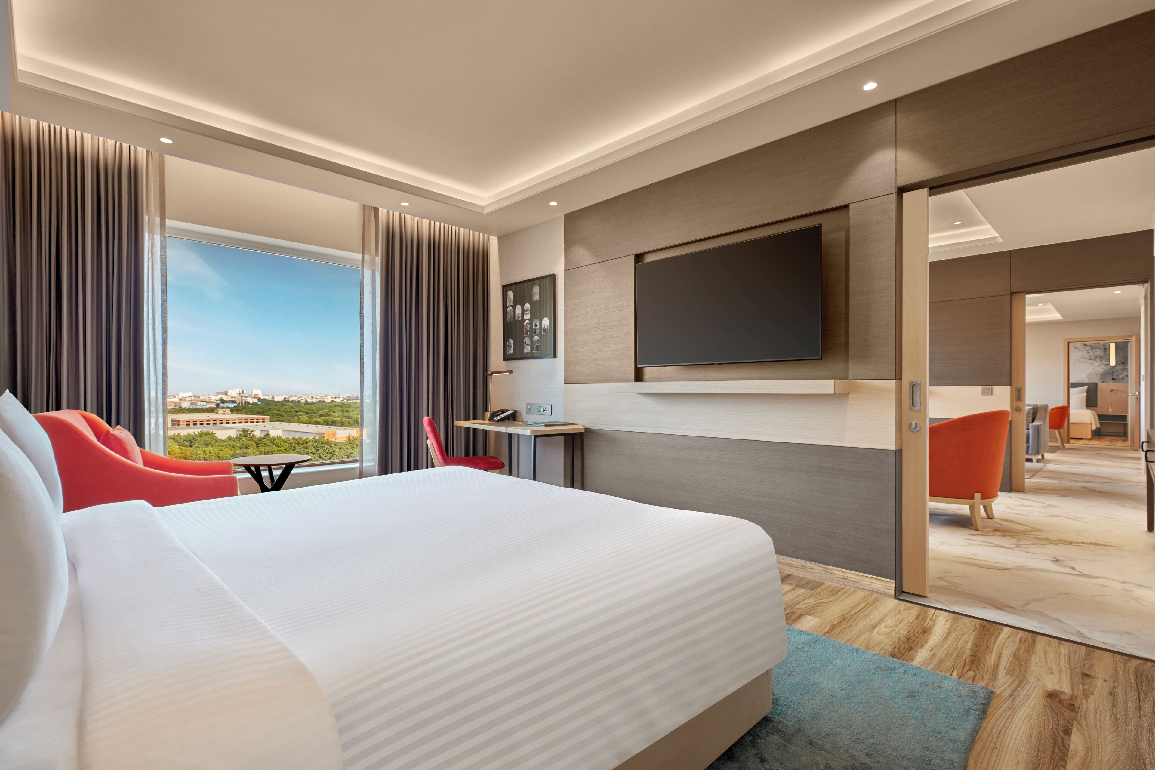 Una camera d'albergo moderna con un letto grande, una scrivania, una TV e vista sulla città.