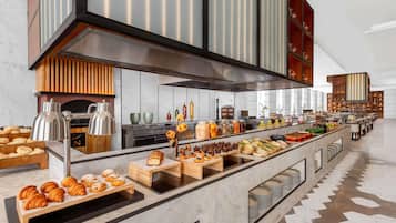 A modern kitchen with a marble countertop, various food items, and a large overhead range hood.