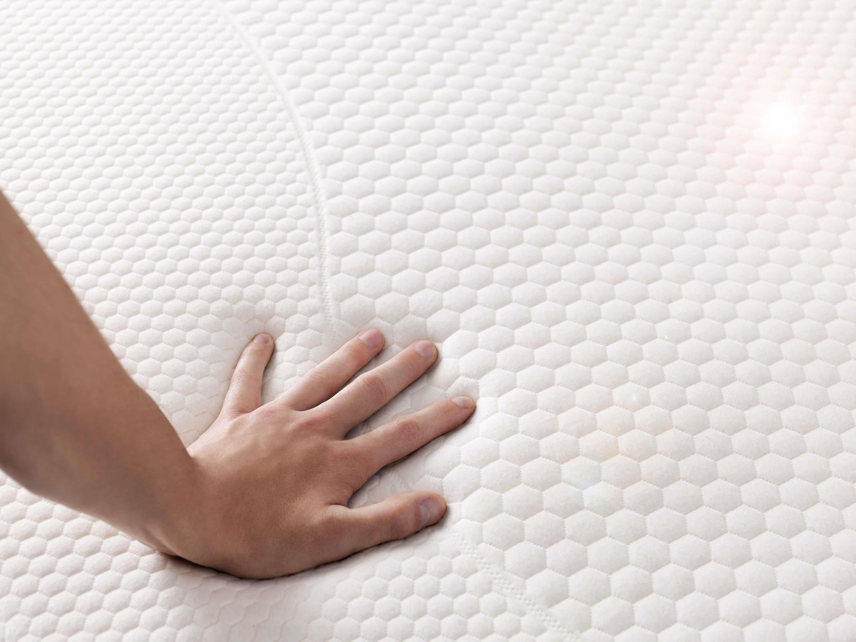 A hand resting on a textured, honeycomb-patterned surface.