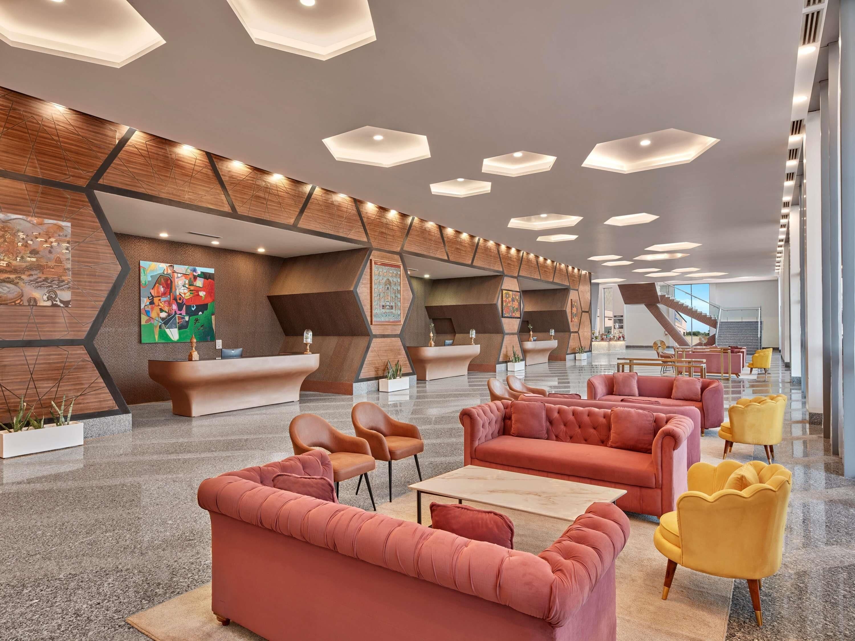 Een moderne lobby met een receptiebalie, zithoeken en een trap.