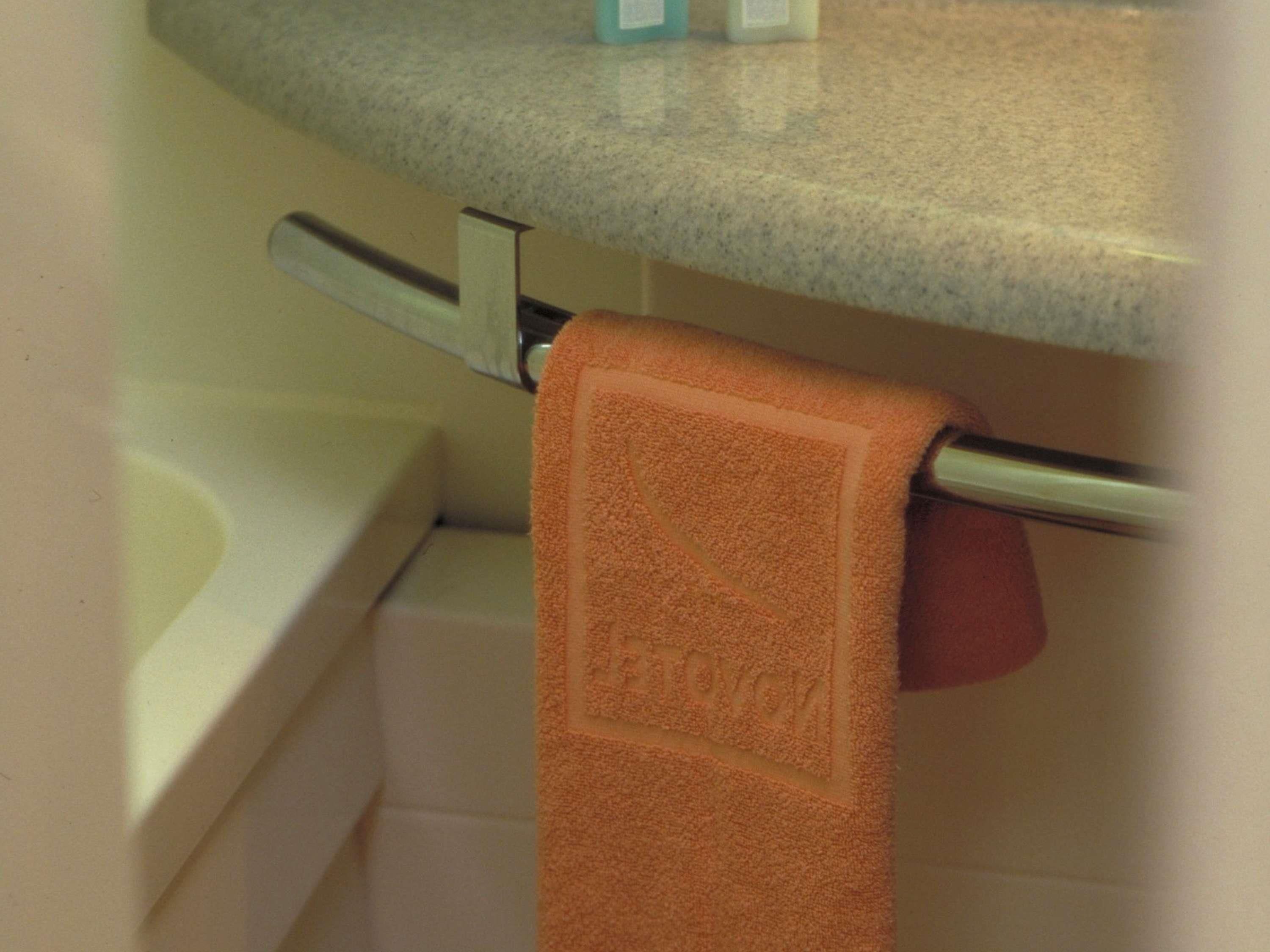 Ein Badezimmer mit einem Handtuch an einem Metallhandtuchhalter, einer weißen Badewanne und einer Granit-Arbeitsplatte über dem Waschbecken.